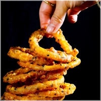 Zes huisgemaakte krokante uienringen geserveerd met saus gekozen door de chef.